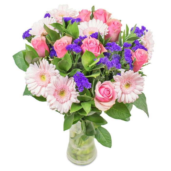 A beautifully detailed bouquet rests in a transparent glass vase, its every detail reflecting the thoughtful craft of a Lower Clapton florist. At the centre, 7-9 pink roses reveal the classic spiral of their petals-some still tightly budded, others just beginning to open-expressing tender vibrancy and romance. Interspersed are 5-7 pale pink Gerbera daisies with large, open heads and nearly white centres, contributing soft, ruffled texture to the bouquet. Clusters of vivid purple statice are scattered throughout, lending pockets of rich colour and intriguing contrast, reminiscent of the botanical diversity celebrated in Hackney's green spaces. The bouquet's foundation is a bed of deep green foliage, which sets off the gentle pinks and purples and radiates a sense of lushness and freshness. The clear vase reveals neatly trimmed stems, immersed in water that glimmers in the light streaming through a Lower Clapton window. Suited for birthdays, anniversaries, Mother's Day, or simply to celebrate life's everyday joys, this bouquet brings an atmosphere of celebration and heartfelt affection to any home or office along Clapton Terrace, capturing both the beauty and spirit of the local area.