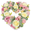 A lush, heart-shaped floral wreath fills the frame, glowing softly against a crisp white background and conveying a deep sense of tenderness and remembrance. The heart is densely packed with blooms, creating a seamless, cushion-like surface where creamy yellow and ivory roses gently rise above the surrounding flowers as calm focal points. Their elegant, spiralling petals feel almost touchable, offering a sense of quiet strength. Around them, clusters of pastel pink carnations add fullness and a delicate, frilled texture, their soft edges evoking comfort and kindness. Deeper tones of pink and mauve lisianthus are peppered throughout the design, their more open, cup-shaped flowers and subtle shading introducing visual depth, like pools of gentle colour you might glimpse in local gardens near Clapton Pond in spring. Threading through the entire wreath, silvery eucalyptus leaves curve gracefully, their muted green-grey tones cooling the palette and giving the arrangement a modern, soothing character. Small yellow-green buds appear here and there, fresh and tightly closed, a reminder of life's ongoing rhythm even amid farewell. The overall effect is one of quiet luxury and heartfelt care, as if crafted slowly and thoughtfully by a florist who understands the needs of grieving families in Lower Clapton. This heart-shaped tribute would sit beautifully beside a casket, on an easel at a crematorium, or at a memorial reception, expressing sympathy, gratitude, and enduring love for someone deeply missed within the Hackney community.
